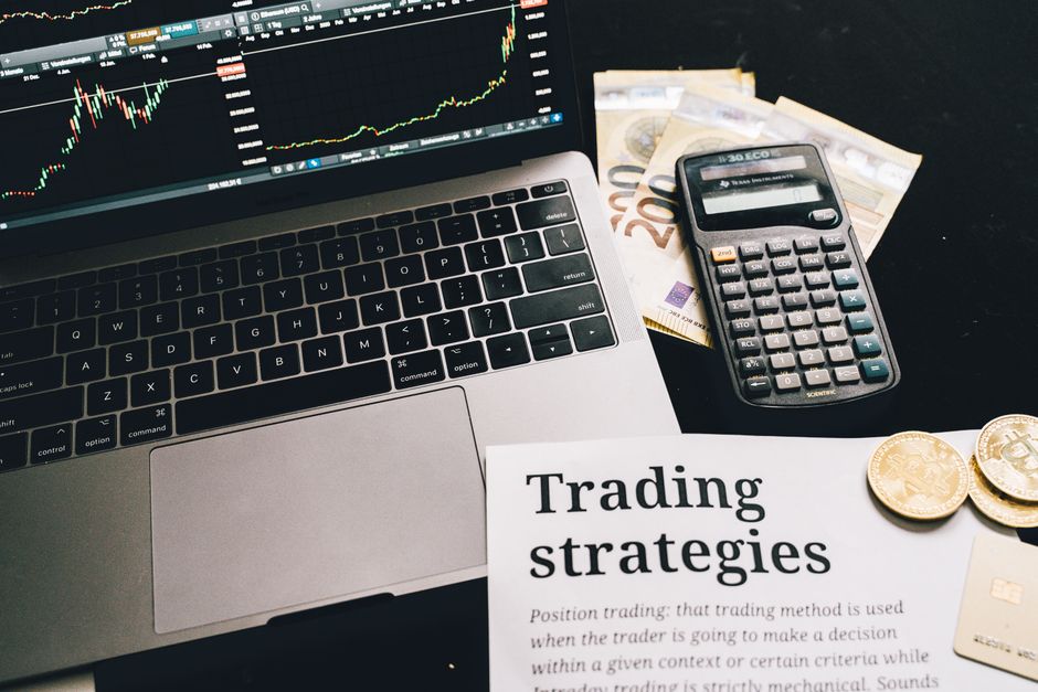 Een professional die werkt met trading software op een laptop, met grafieken en analyses op het scherm, in een moderne kantooromgeving.